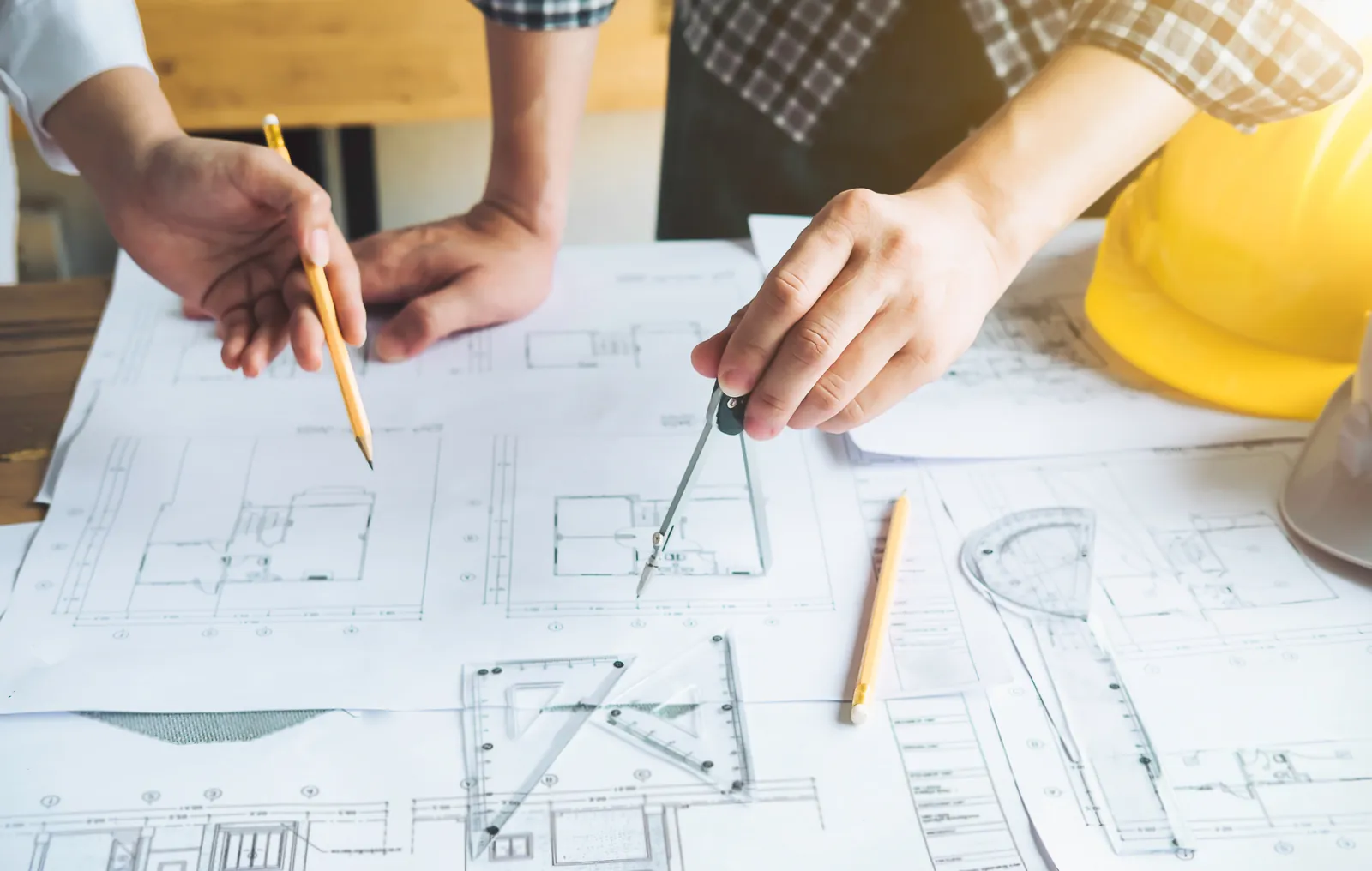Projeto arquitetônico impresso sobre mesa de trabalho com instrumentos de desenho