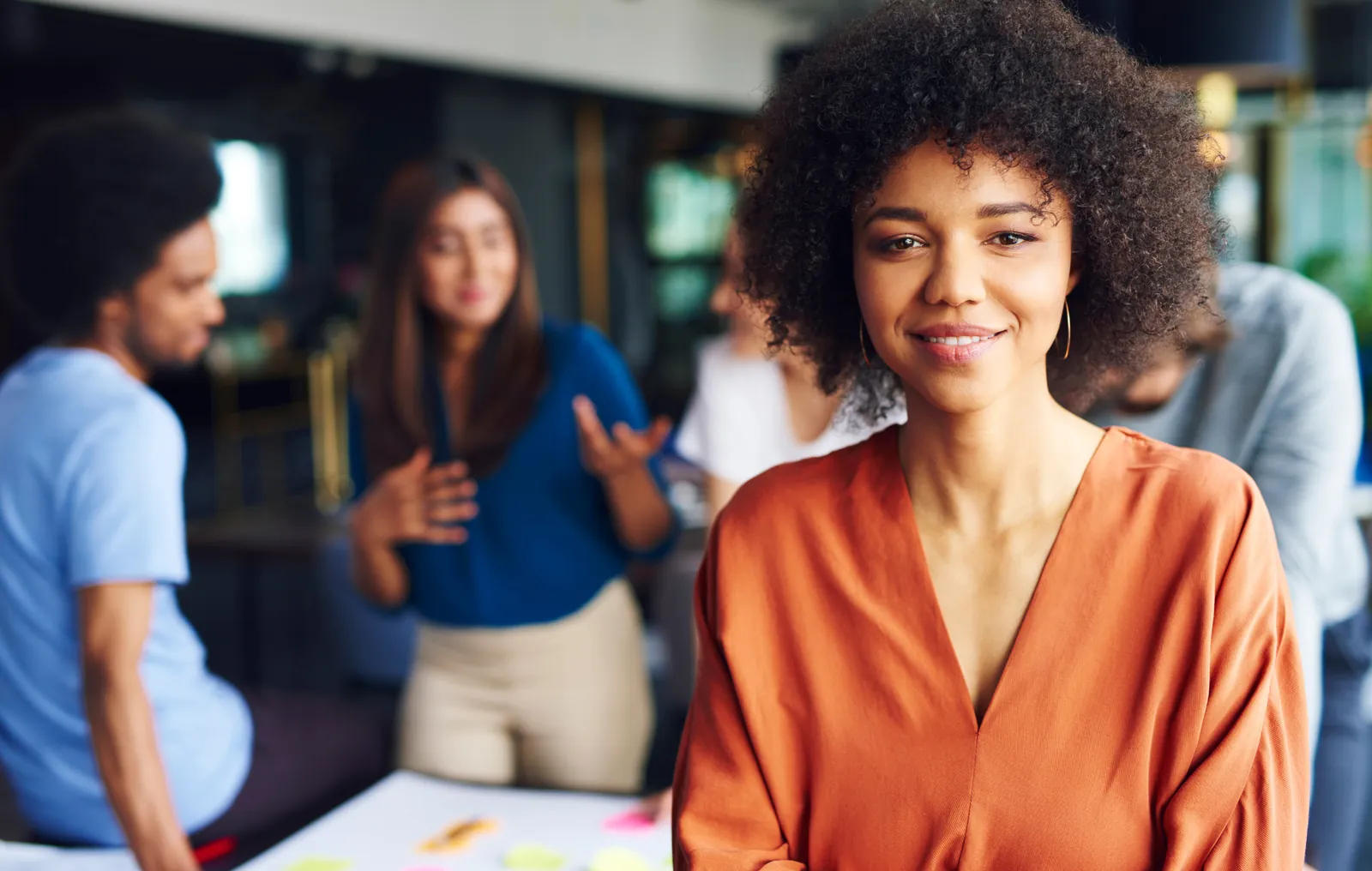 Reunião de equipe em ambiente de trabalho, com pessoas conversando ao redor de uma mesa